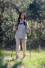 Donna felice con bastoni da trekking nella foresta — Foto stock