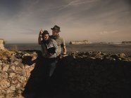 Stilvoller Mann mit Hut und elegante Frau mit Mütze lesen Bände in der Nähe von Felsen an der Küste des Meeres und wunderbaren Himmel — Stockfoto