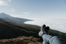 Ноги неузнаваемых туристов лежат и отдыхают на вершине холма — стоковое фото