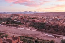 Desde el casco antiguo con construcciones de piedra cerca del estrecho río entre el desierto y el hermoso cielo con nubes en Marrakech, Marruecos - foto de stock