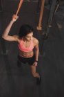 Jovem mulher esportiva magro em sportswear fazendo puxar para cima exercícios na barra horizontal no ginásio — Fotografia de Stock