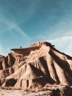 Каньйонні пісковикові пагорби з мандрівниками зверху на тлі прозорого блакитного неба — стокове фото