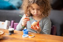Toddler girl painting egg at table — Stock Photo