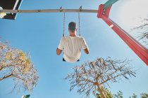 Man swinging on playground in sunlight — Stock Photo