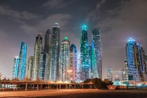 Céu cinzento e nublado sobre arranha-céus brilhantemente iluminados numa noite maravilhosa no Dubai — Fotografia de Stock