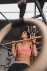 Donna in abbigliamento sportivo facendo esercizi di pull up sulla barra orizzontale in palestra — Foto stock