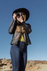 Female photographer standing with camera and looking at hills in desert — Stock Photo