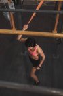 Молода струнка жінка в спортивному одязі робить вправи на горизонтальному барі в спортзалі — стокове фото