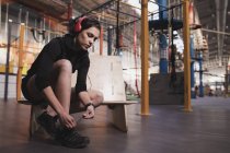 Вид сбоку на женщину в наушниках, слушающую музыку и стирающую обувь в спортзале — стоковое фото