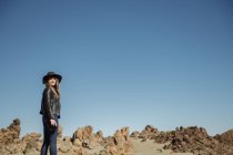 Fotografo donna in piedi con la macchina fotografica e guardando le colline nel deserto — Foto stock