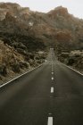 Vista prospectiva para estrada de asfalto em terra seca que leva a montanhas — Fotografia de Stock