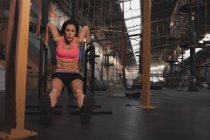 Frau in Sportbekleidung macht in großer Turnhalle Klimmzugübungen am parallelen Barren — Stockfoto