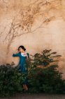 Привлекательная арабская женщина в платье между растениями у стены — стоковое фото