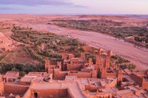 Da cidade velha acima com construções de pedra perto do rio estreito entre o deserto e o céu bonito com nuvens em Marraquexe, Marrocos — Fotografia de Stock