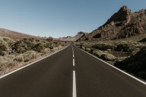 Perspectiva de la carretera de asfalto en tierra firme que conduce a las montañas - foto de stock