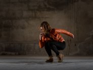 Junge Frau tanzt in grauem Zimmer — Stockfoto