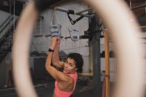 Mujer en ropa deportiva haciendo ejercicios de pull up en barra horizontal en el gimnasio - foto de stock
