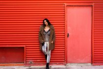 Donna alla moda con smartphone vicino alla parete — Foto stock