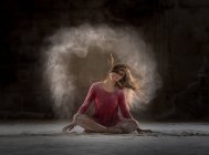 Молода жінка танцює і використовує порошок у темряві — стокове фото