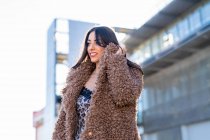 Mulher alegre que envolve no casaco na rua — Fotografia de Stock