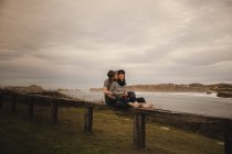 Junges Paar spielt auf Handtrommel in der Nähe der Küste bei bewölktem Himmel — Stockfoto
