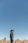 Fotógrafa de pie con cámara y mirando colinas en el desierto - foto de stock