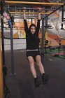 Jeune femme en vêtements de sport faire des exercices pull up sur barre horizontale dans la salle de gym — Photo de stock