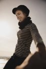 Elegante donna in berretto sulla costa vicino al mare ondulante — Foto stock