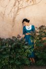 Attractive Arabic woman in dress between plants near wall — Stock Photo