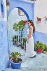 Hermosa mujer caminando entre casas azules en Marrakech - foto de stock