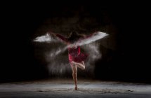 Giovane donna che balla e usa polvere nell'oscurità — Foto stock