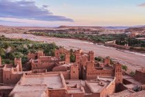Desde el casco antiguo con construcciones de piedra cerca del estrecho río entre el desierto y el hermoso cielo con nubes en Marrakech, Marruecos - foto de stock