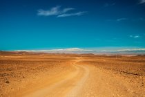 Malerischer Blick auf die Landstraße zwischen Wüste mit wildem Land und blauem Himmel in Marrakesch, Marokko — Stockfoto