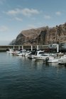 Row of small motorboats moored on quay at cliff in sunny day — Stock Photo