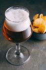 Склянка пива і чіпсів на темному гранжевому фоні — стокове фото