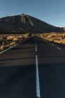 Vista prospectiva para estrada de asfalto em terra seca que leva a montanhas — Fotografia de Stock