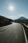 Perspective view to asphalt road in dry land leading to mountains — Stock Photo