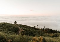 Зверху асфальтована дорога на зеленому пагорбі та вид на хмарний пейзаж — стокове фото