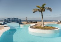 Kleine Brücke und Palme am blauen Pool im Hotel — Stockfoto