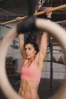 Молодая женщина в спортивной форме делает упражнения на горизонтальной панели в тренажерном зале — стоковое фото