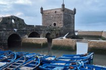 Blue fishing boats moored at historic construction in Essaouira, Morocc — Stock Photo