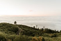 Зверху асфальтована дорога на зеленому пагорбі та вид на хмарний пейзаж — стокове фото