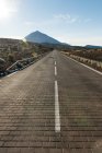 Perspectiva de la carretera de asfalto en tierra firme que conduce a las montañas - foto de stock