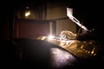 Uomo in casco di saldatura che lavora con prodotto metallico su piccola fonderia — Foto stock