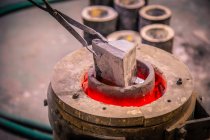 Closeup of metal product melting in crucible on little foundry on blurred background — Stock Photo