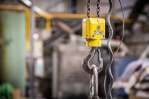 Closeup of hoisting machine with iron chains on little foundry on blurred background — Stock Photo