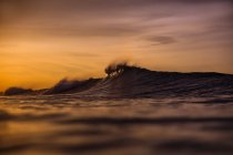 Ola de agua de primer plano de mar y cielo nublado al atardecer - foto de stock