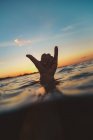 Closeup hand of human showing shaka sign above water surface with ripple and blue heaven in evening on Bali, Indonesia — Fotografia de Stock