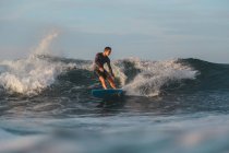 Surf maschile tra acqua di mare ondulata con spruzzi a Bali, Indonesia — Foto stock