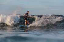 Surf maschile tra acqua di mare ondulata con spruzzi a Bali, Indonesia — Foto stock
